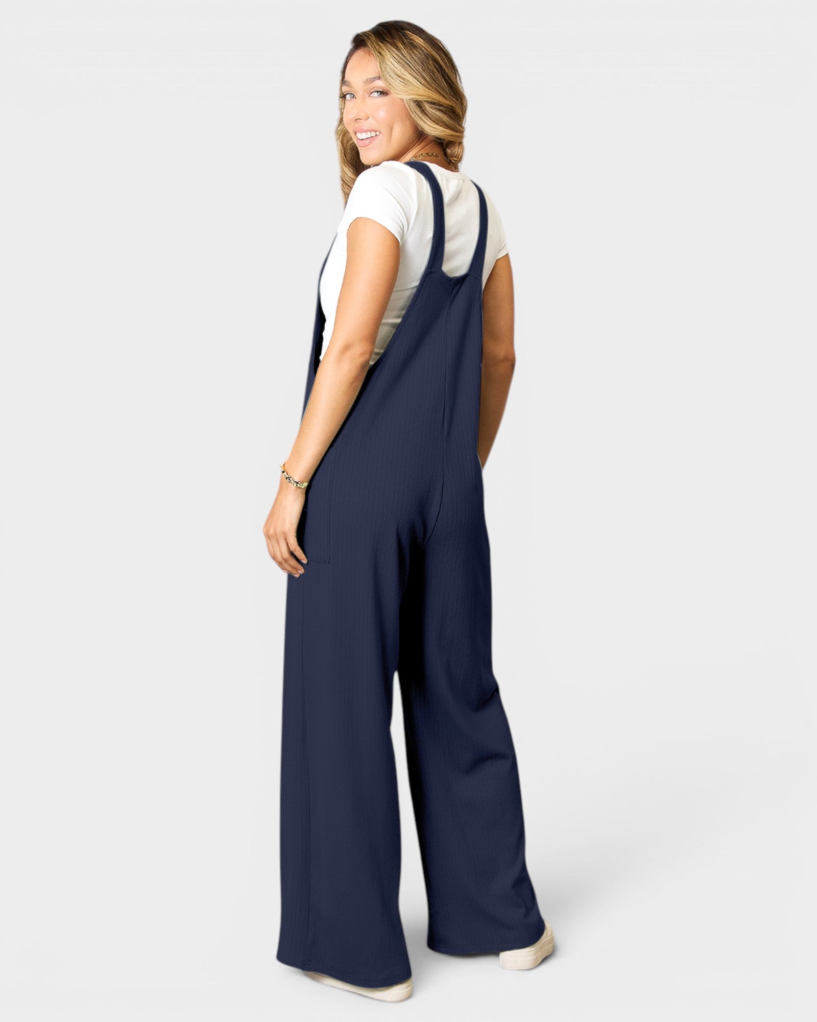 Woman wearing navy blue overalls on a white background