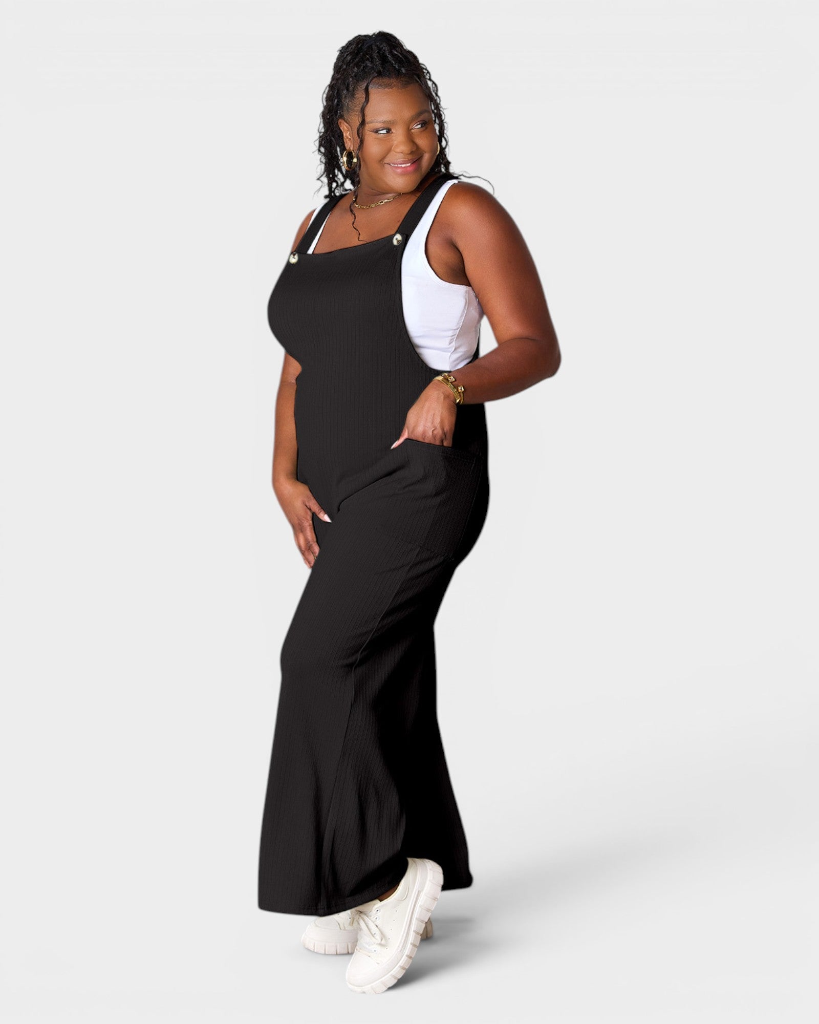 Woman wearing a black dress over a white top on a plain background