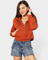 Woman wearing a rust-colored pullover with a zipper and blue denim shorts on a white background