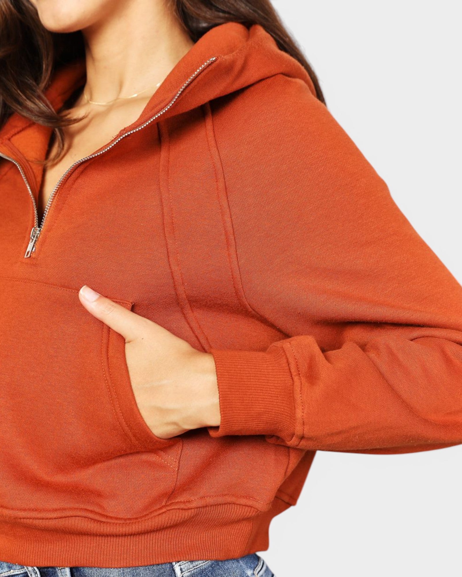Person wearing a rust-colored hoodie with a white background