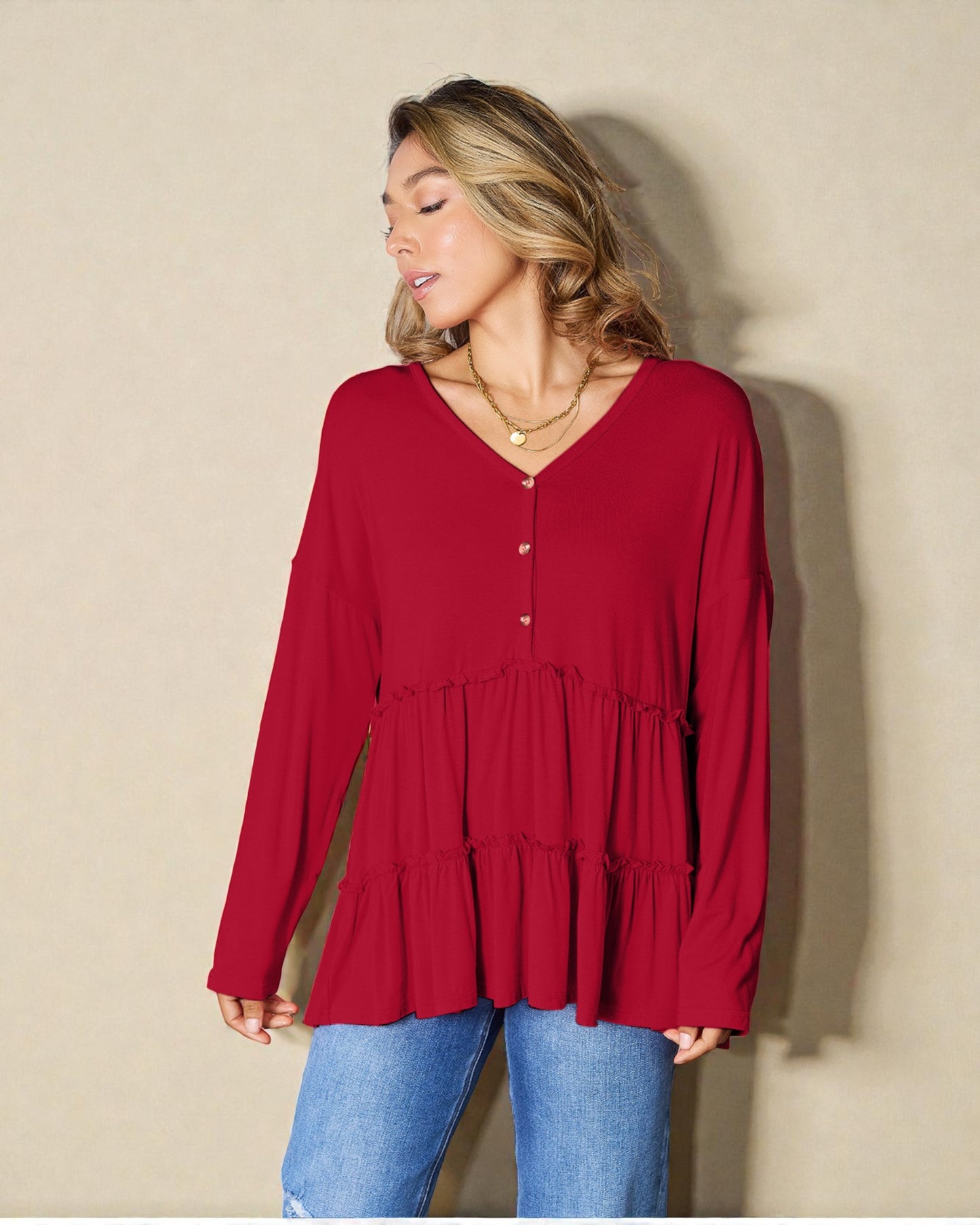 Woman wearing a red long-sleeve top against a beige background