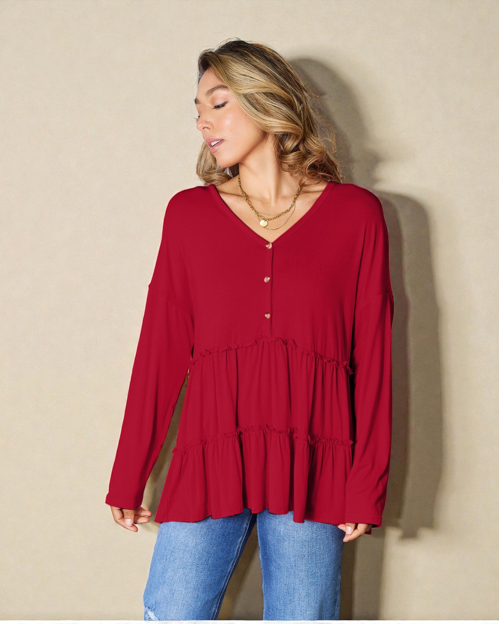 Woman wearing a red long-sleeve top against a beige background