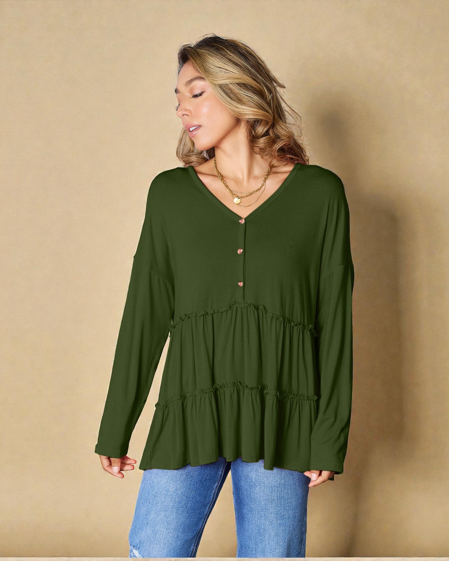 Woman wearing a green long-sleeve top against a beige background