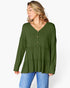 A woman wearing a long-sleeve olive green tiered blouse with a buttoned V-neckline, paired with blue jeans, against a plain white background.