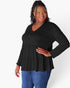A woman modeling a black long-sleeve peplum top with a tiered ruffle hem and button placket, paired with blue jeans, against a plain white studio background.