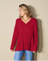 Woman wearing a red long-sleeve top against a beige background