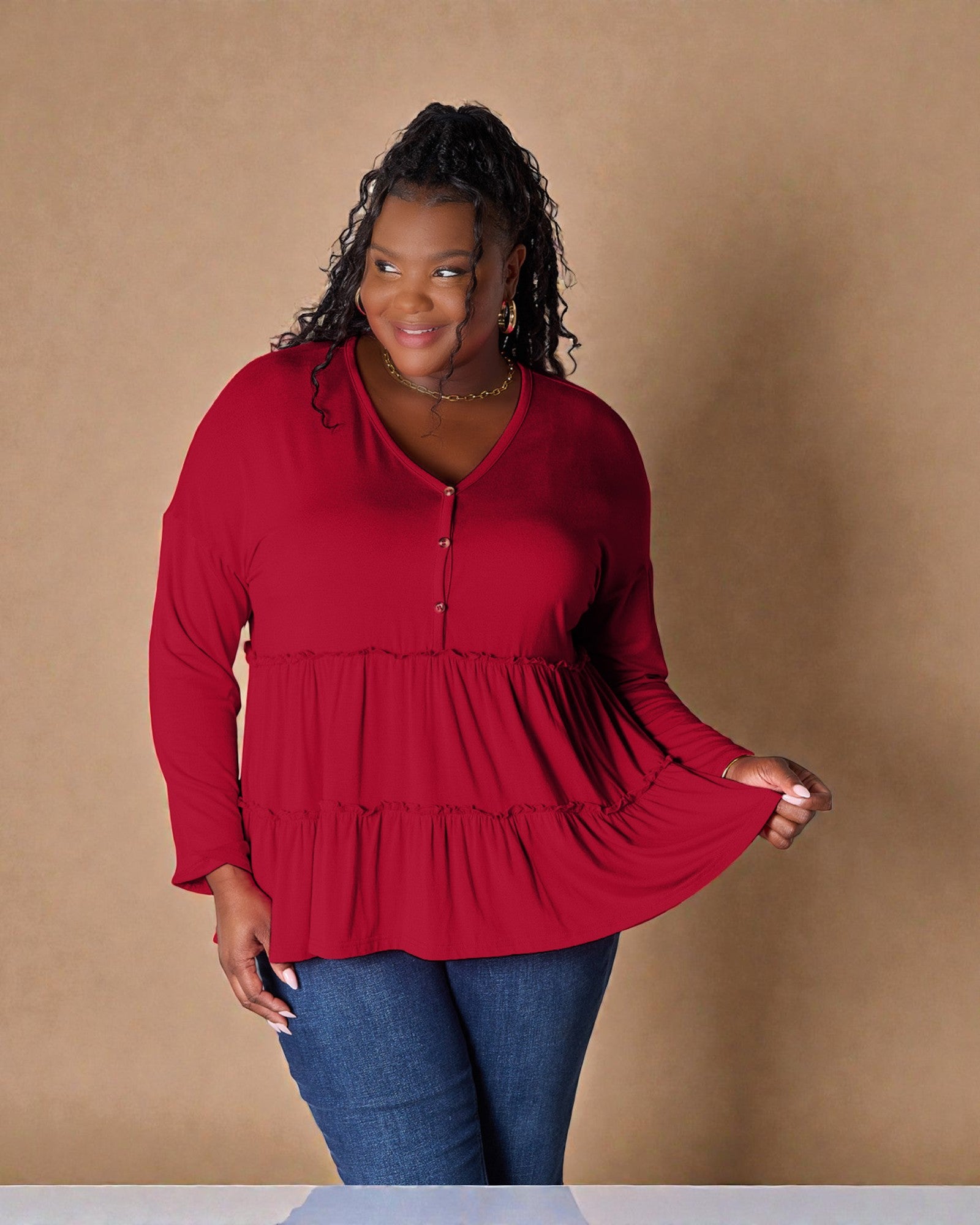 Woman wearing a red blouse with long sleeves and a brown background