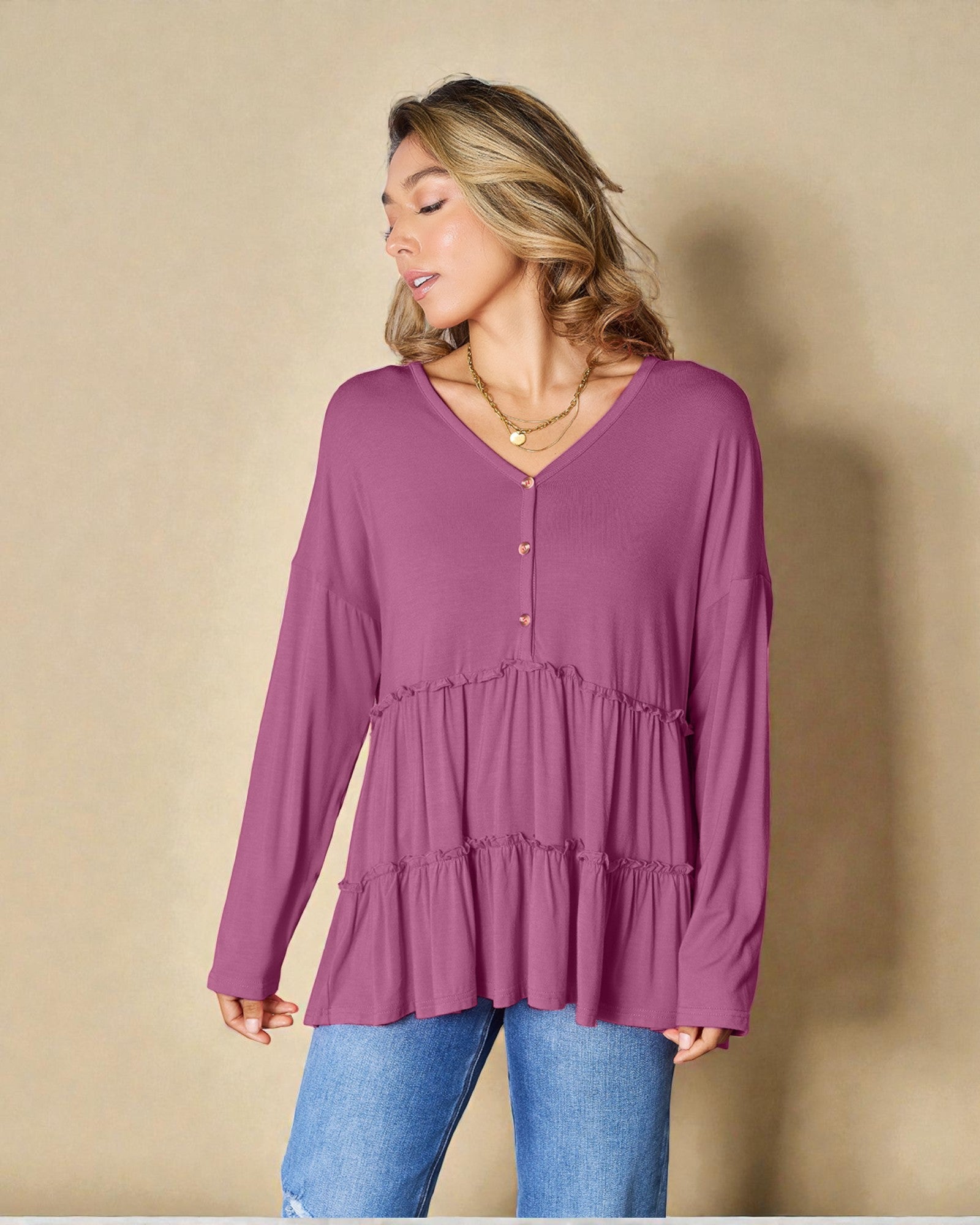 Woman wearing a purple long-sleeve top against a beige background