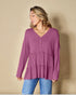 Woman wearing a purple long-sleeve top against a beige background