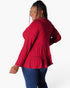 A woman modeling a red long-sleeve top with a tiered ruffle hem, shown from a back-three-quarter angle against a plain white studio background.