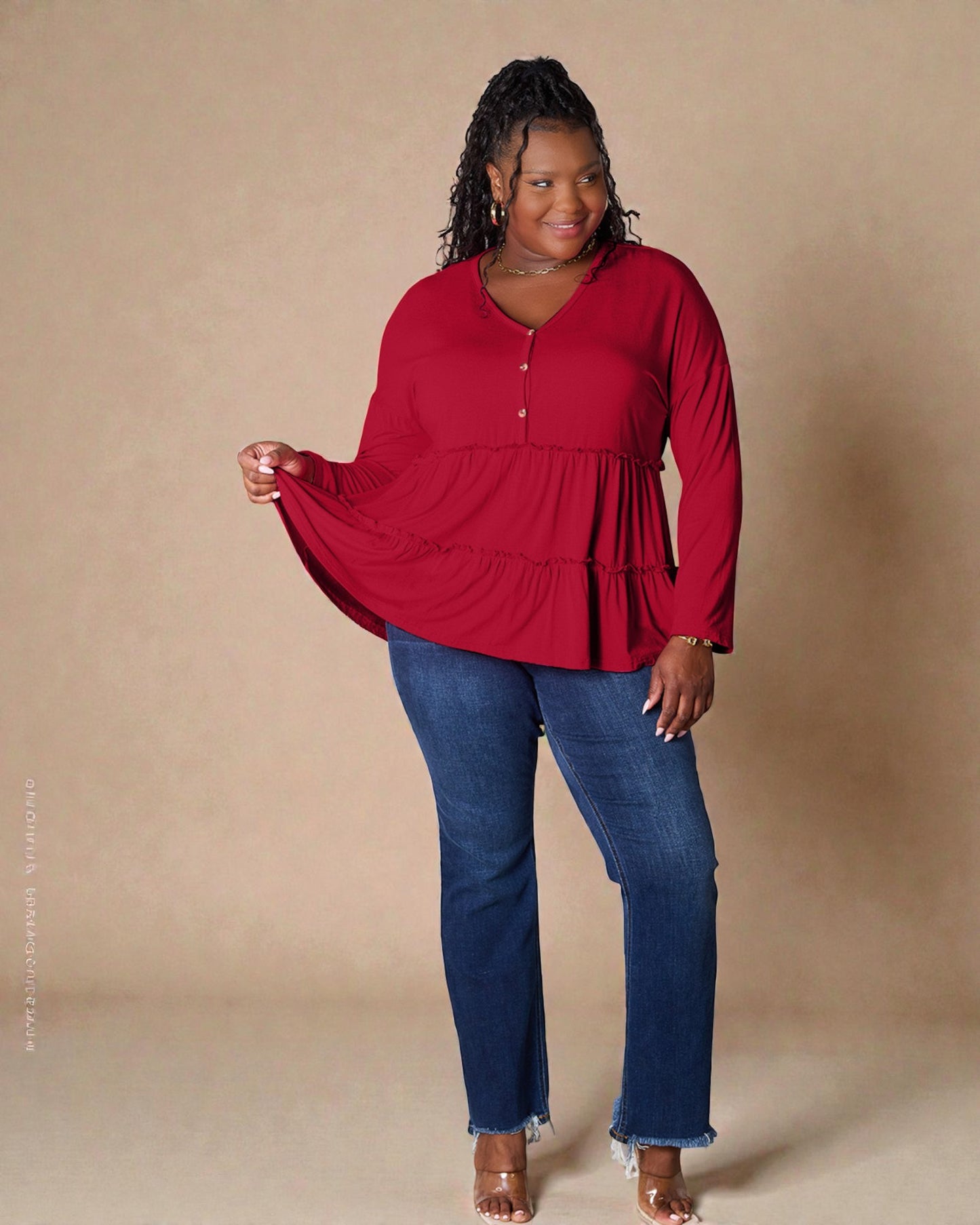 Woman wearing a red blouse and blue jeans against a beige background