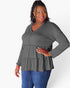 A woman modeling a dark gray long-sleeve top with a tiered ruffle hem and a buttoned V-neckline, paired with blue jeans against a plain white background.