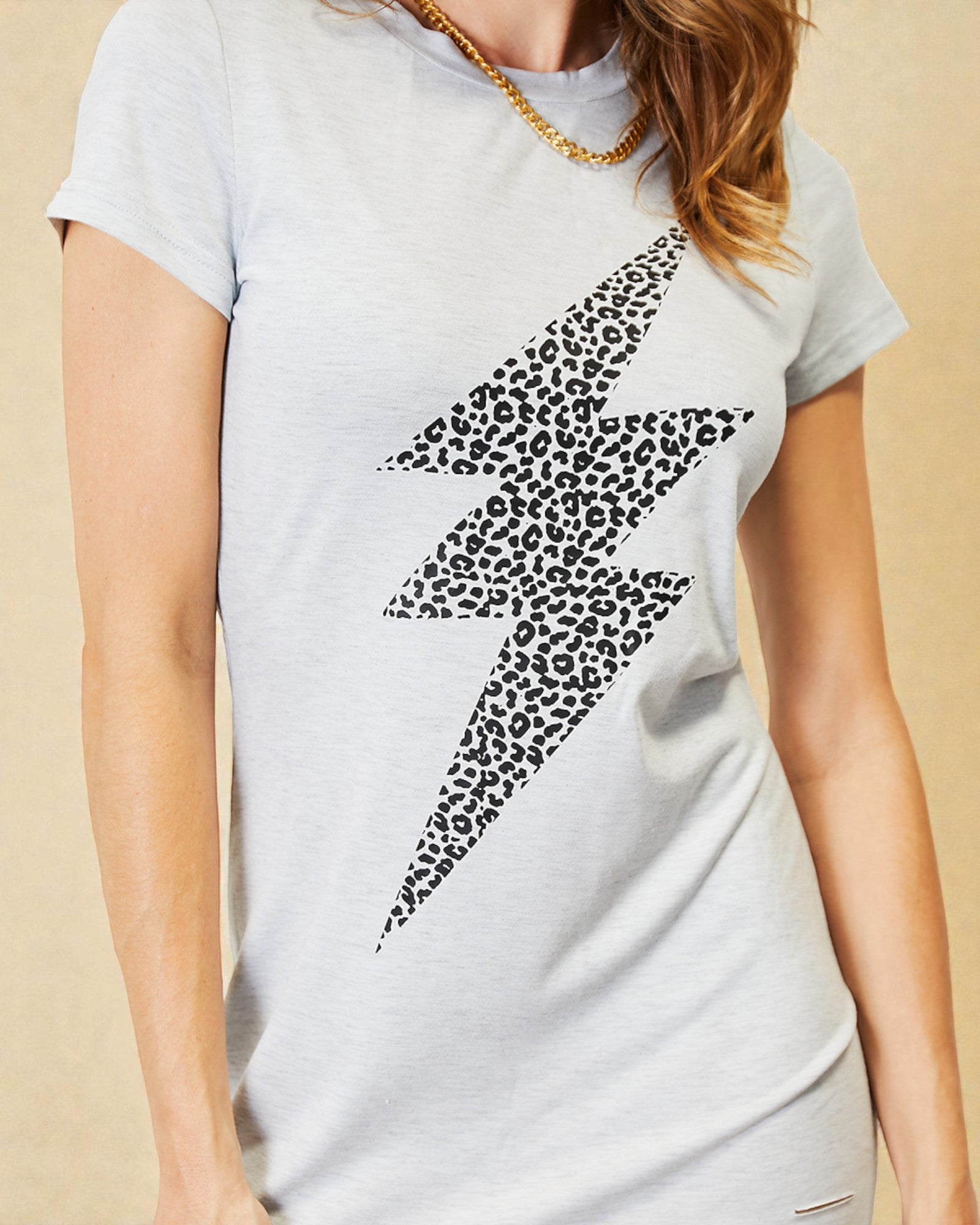 Gray t-shirt with a black leopard print lightning bolt design on a beige background
