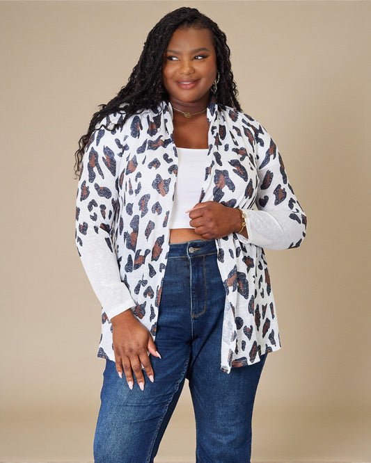 Woman wearing a leopard print cardigan over a white top and blue jeans on a beige background
