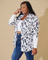 Woman wearing a leopard print cardigan over a white shirt and blue jeans on a beige background