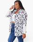 A woman modeling a white long-sleeve button-up shirt with a brown and black leopard print pattern, worn open over a white crop top and blue jeans, against a plain white background.