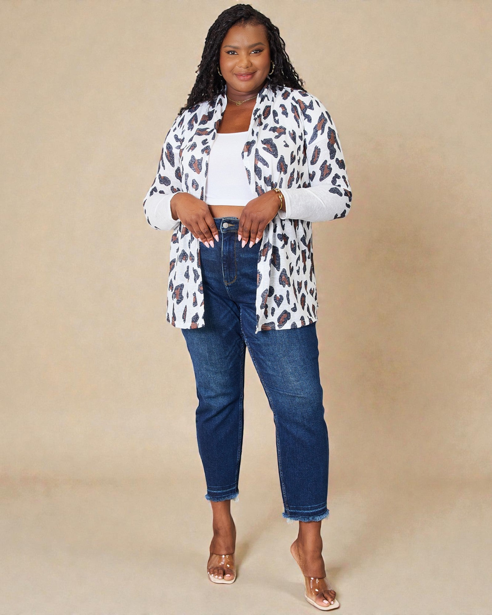Woman wearing a leopard print shirt, white top, and blue jeans on a beige background