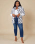 Woman wearing a leopard print shirt, white top, and blue jeans on a beige background