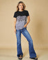 Woman wearing a black t-shirt with a leopard print design and blue jeans on a beige background