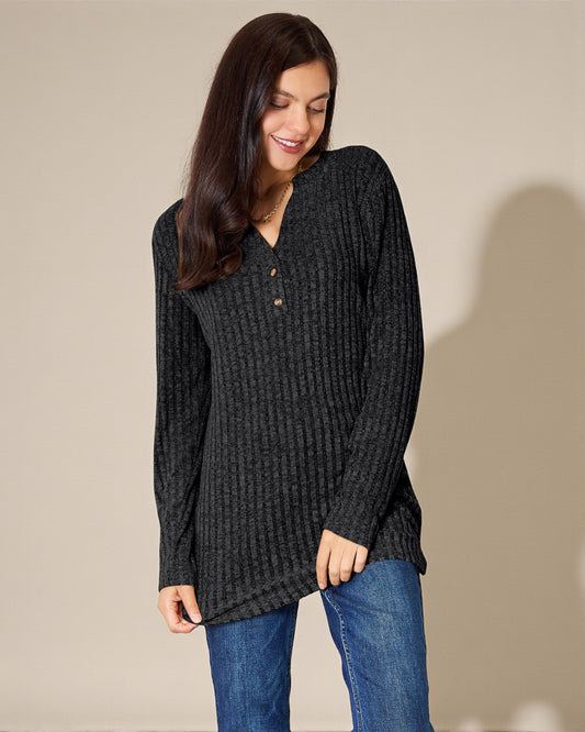 Woman wearing a dark gray textured sweater and blue jeans against a beige background