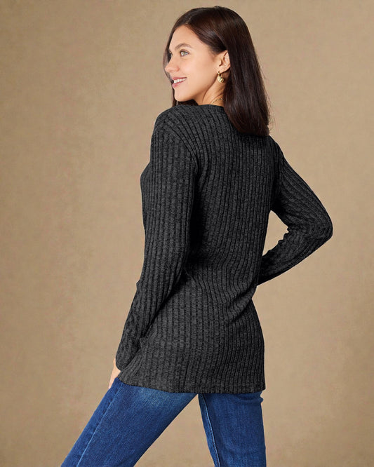 Woman wearing a dark gray ribbed sweater and blue jeans against a beige background
