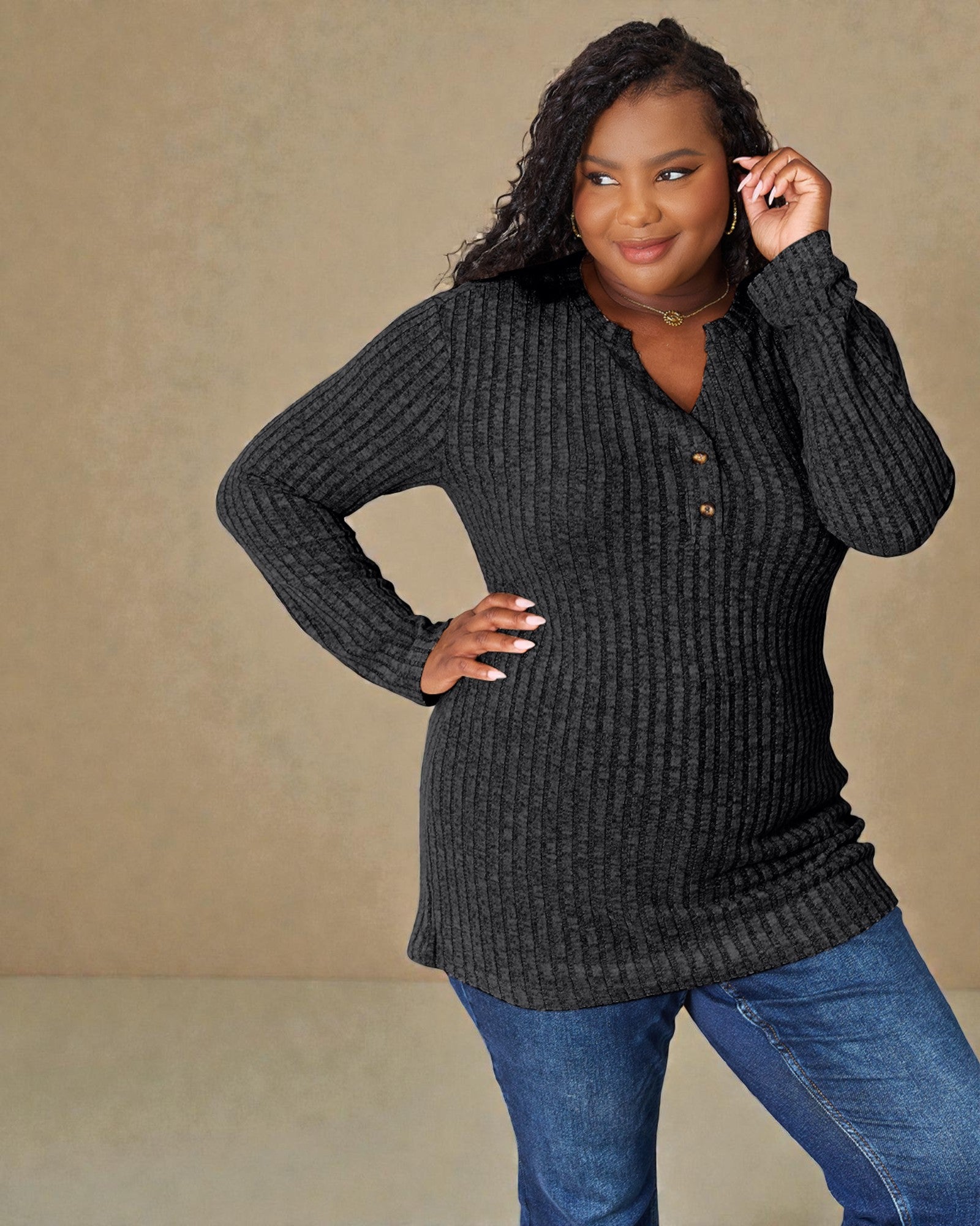 Woman wearing a dark gray textured sweater and blue jeans against a beige background