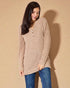 Woman wearing a beige long-sleeve top and blue jeans against a beige background