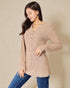 Woman wearing a beige long-sleeve knit top with a plain background