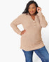 A woman modeling a beige ribbed knit long-sleeve henley top with blue jeans against a plain white studio background.