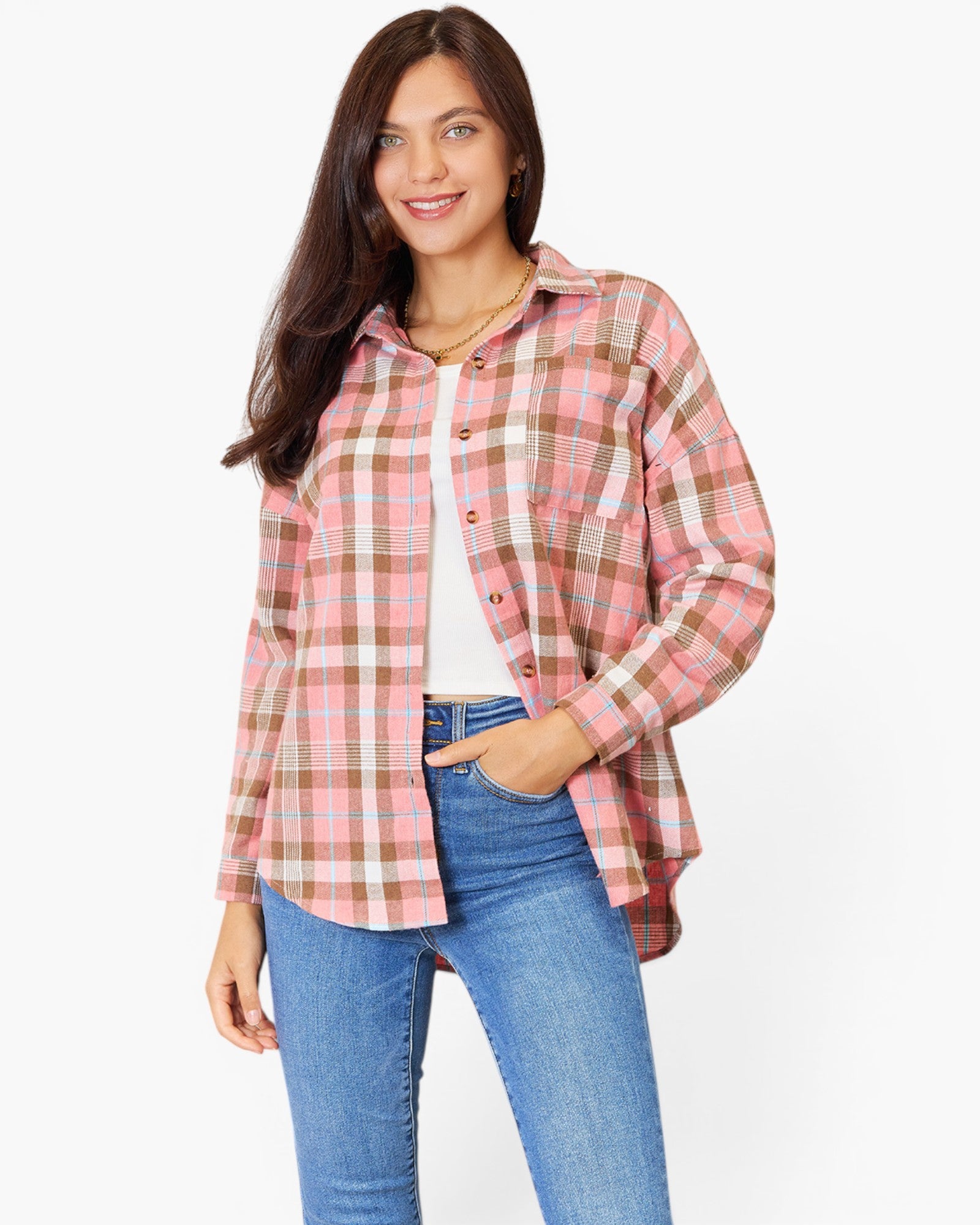 A woman modeling a pink and beige plaid button-up shirt with blue jeans against a plain white background.