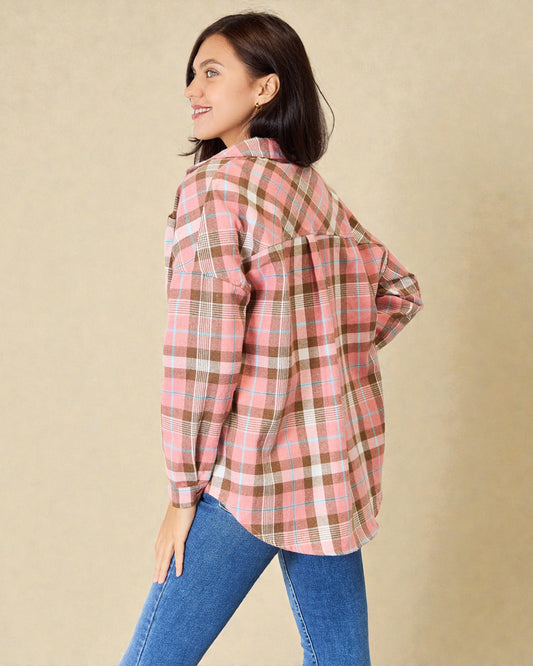 Woman wearing a pink plaid shirt and blue jeans against a beige background
