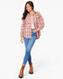 A woman modeling a pink and beige plaid button-up shirt over a white top, paired with blue skinny jeans and brown ankle boots, against a plain white background.