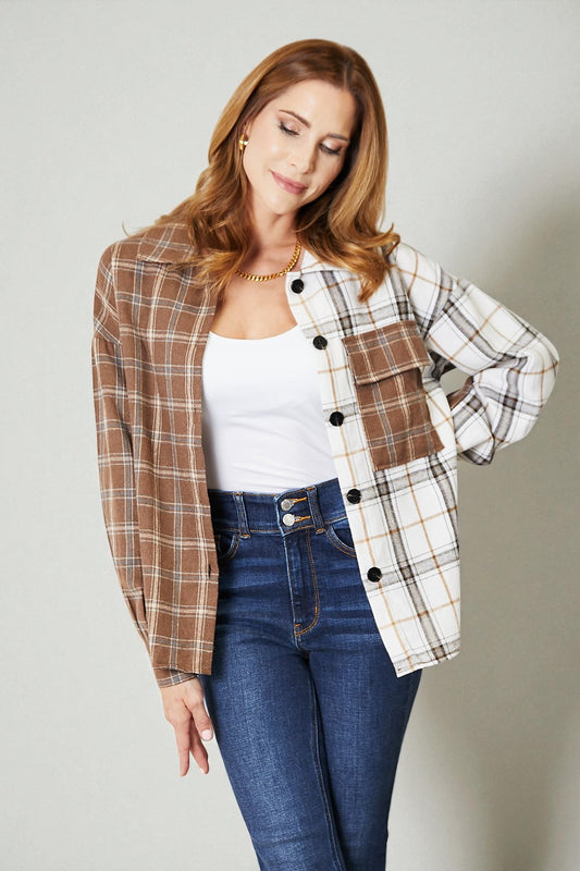 Woman wearing a plaid shirt over a white top and blue jeans on a plain background