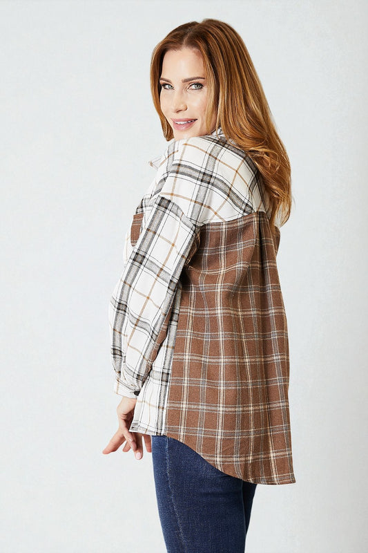 Woman wearing a plaid shirt over a white top on a plain background