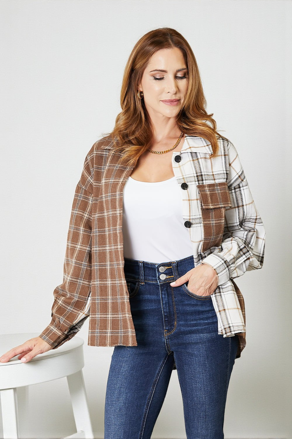 Woman wearing a plaid jacket over a white shirt and blue jeans on a white background