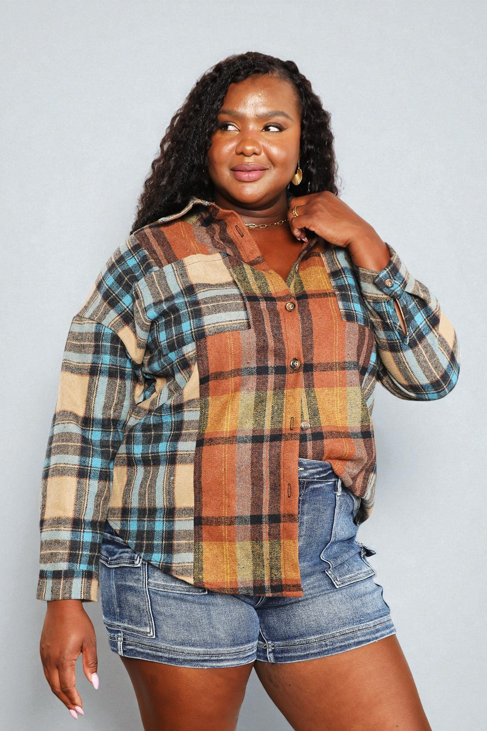 Woman wearing a plaid shirt and denim shorts against a plain background