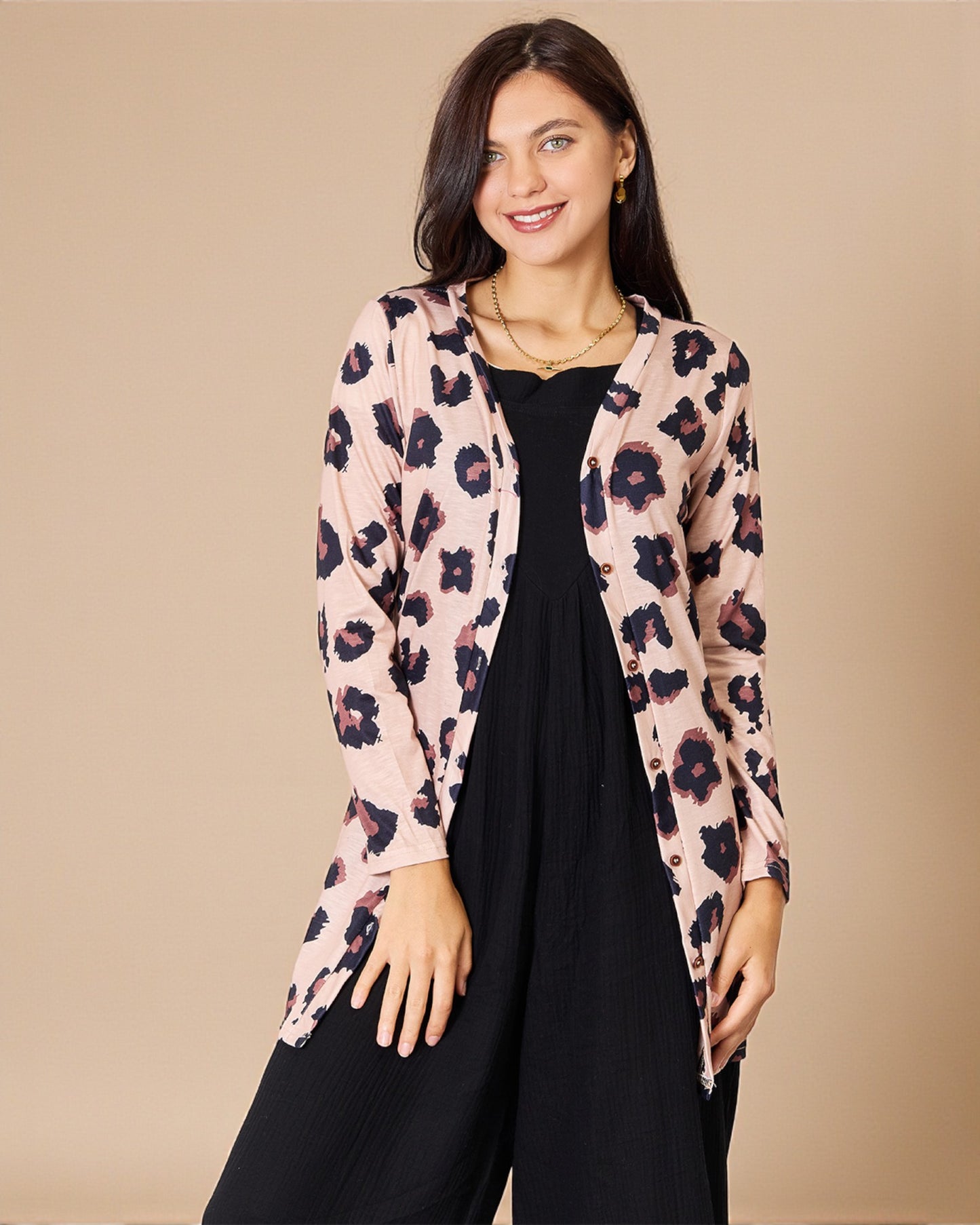 Woman wearing a floral cardigan over a black outfit on a beige background