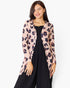 A woman modeling a light pink long-sleeve cardigan with a dark floral print, worn open over a black dress, against a plain white studio background.