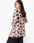 A woman shown from the back wearing a long-sleeve tunic top with a pink, black, and dark red leopard print pattern, paired with black pants, against a plain white background.