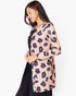 A woman wearing a light pink long-sleeve button-up cardigan with a dark navy and dusty rose floral print, layered over a black dress, against a plain white background.