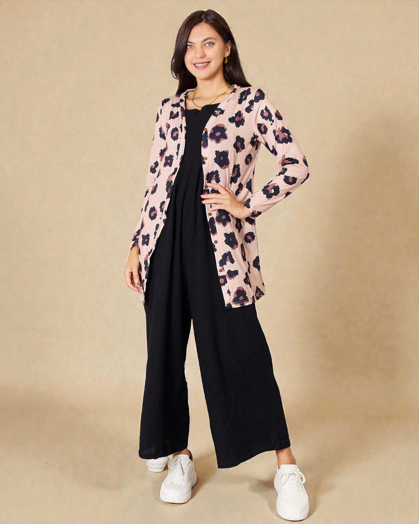 Woman wearing a floral cardigan over a black dress on a beige background