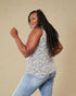 Woman wearing a sleeveless animal print top and jeans against a beige background