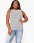 A plus-size woman modeling a sleeveless black and white spotted tank top with light-wash blue jeans against a plain white studio background.