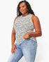 A woman modeling a sleeveless white tank top with a black speckled animal print pattern, paired with light blue jeans, against a plain white studio background.