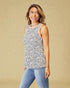 Woman wearing a black and white patterned sleeveless top and blue jeans against a beige background