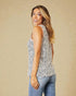 Woman wearing a sleeveless animal print top and blue jeans against a beige background