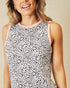 Woman wearing a sleeveless top with a black and white pattern on a beige background