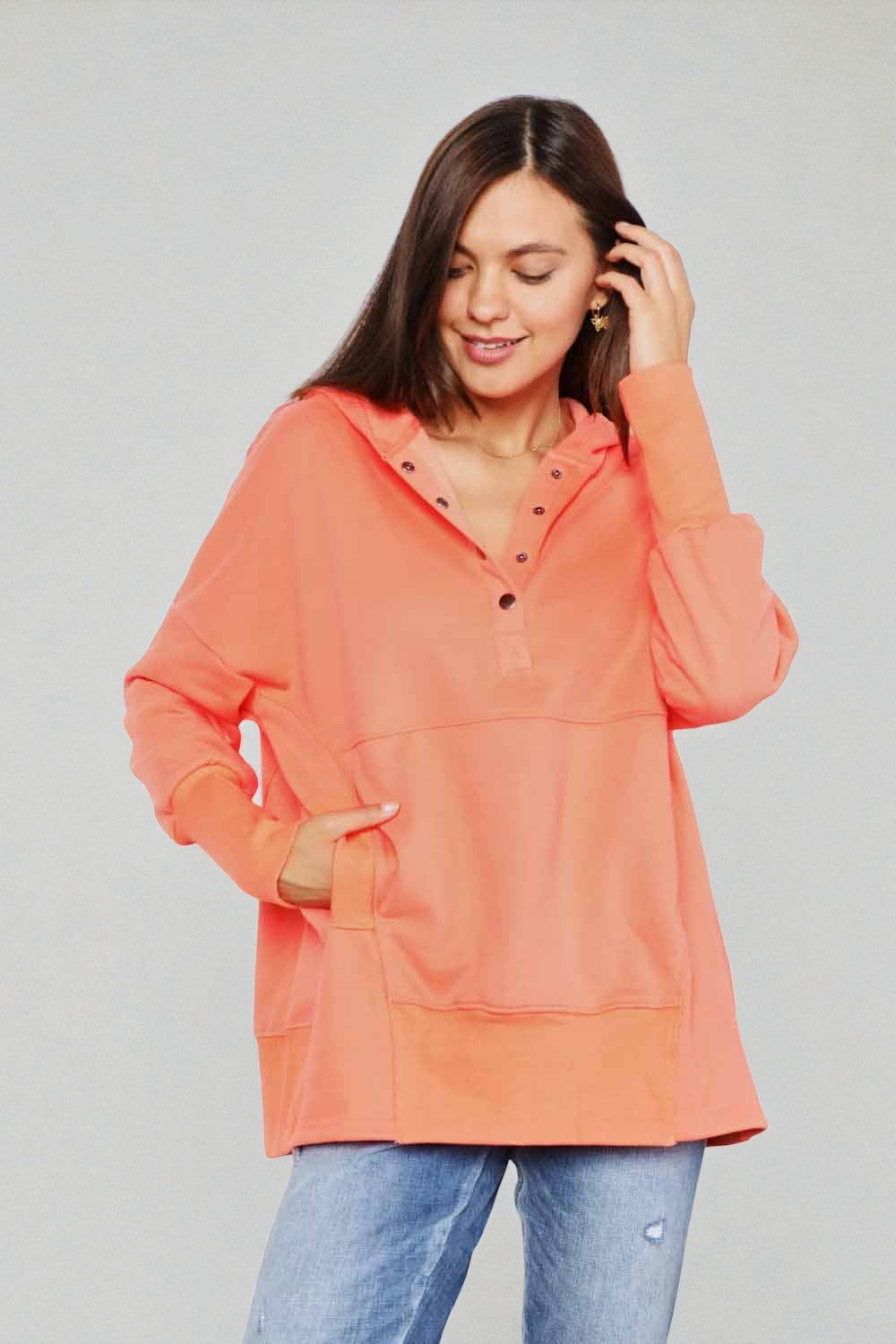 Woman wearing an orange hoodie against a gray background