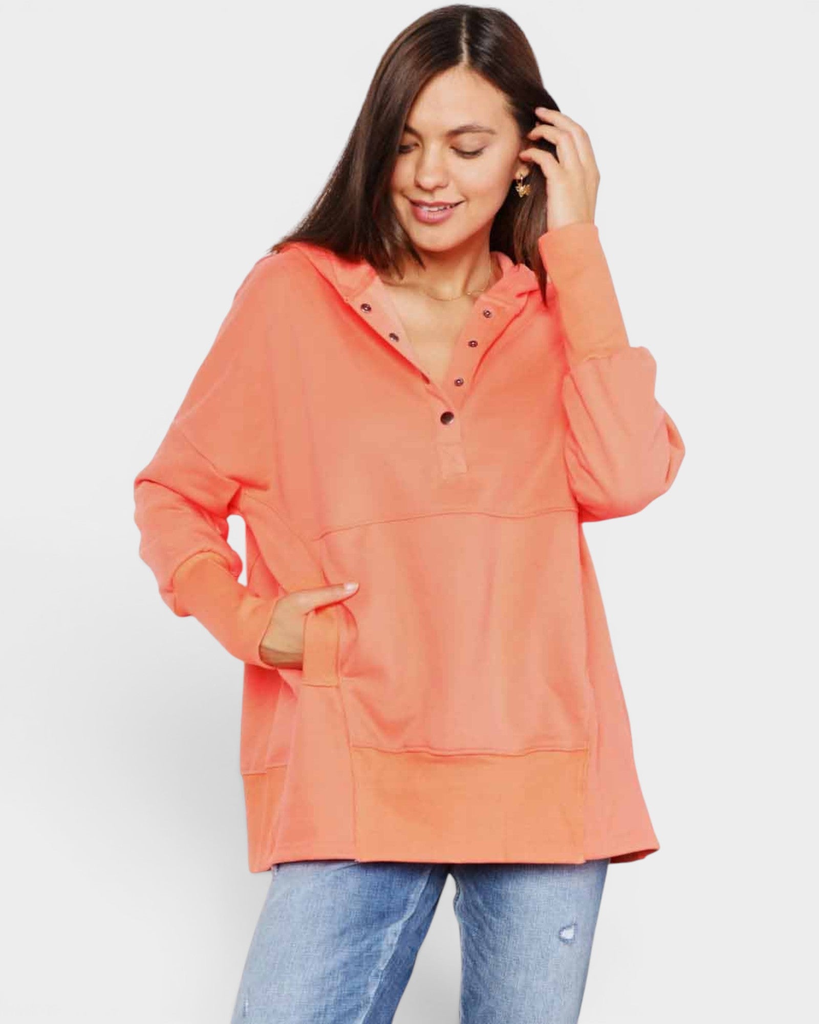 Woman wearing a coral hoodie and blue jeans on a white background