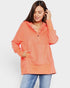 Woman wearing a coral hoodie and blue jeans on a white background